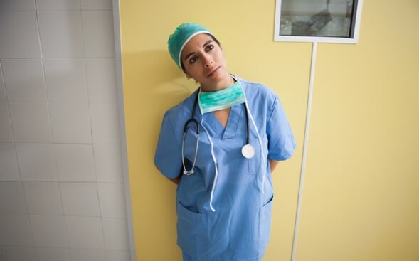 Nurse leaning in hallway looking contemplative Nurse leaning in hallway looking contemplative